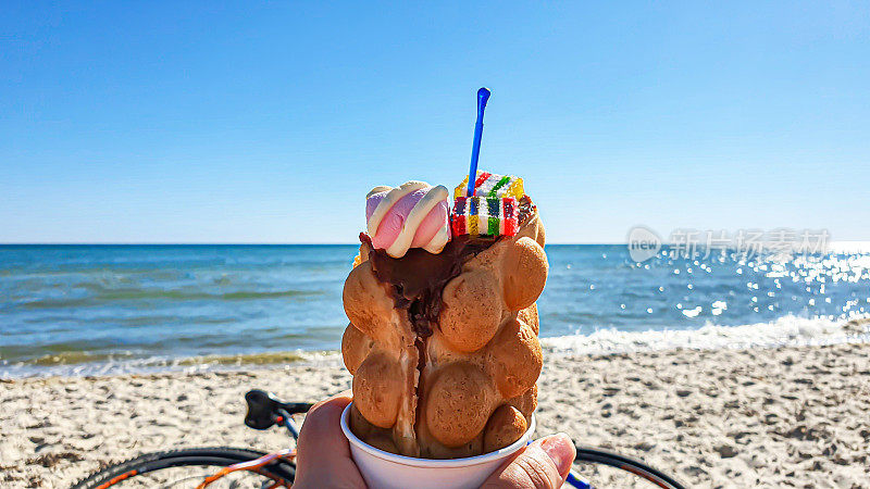 Seascape. Wafer takanchik with ice cream and marmalade on the background of the sea. Azure water, waves foaming on the shore.